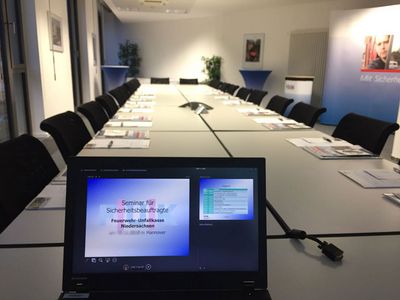 Blick in den Seminarraum mit eingedecktem Tisch und Laptop mit Startbild des Seminars für Sicherheitsbeauftragte