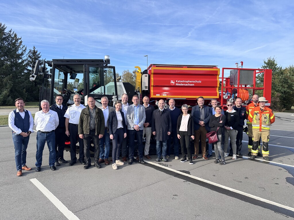 Das Bild zeigt mehrere Menschen vor einem Fahrzeug.
